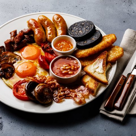 Full fry up English breakfast with fried eggs, sausages, bacon, Full fry up English breakfast with fried eggs, sausages, bacon, black pudding, beans and toasts on gray concrete background